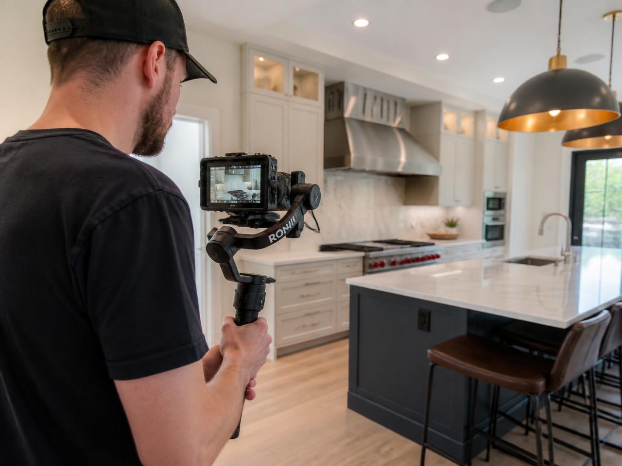 Videographer filming a modern kitchen with a camera on a gimbal